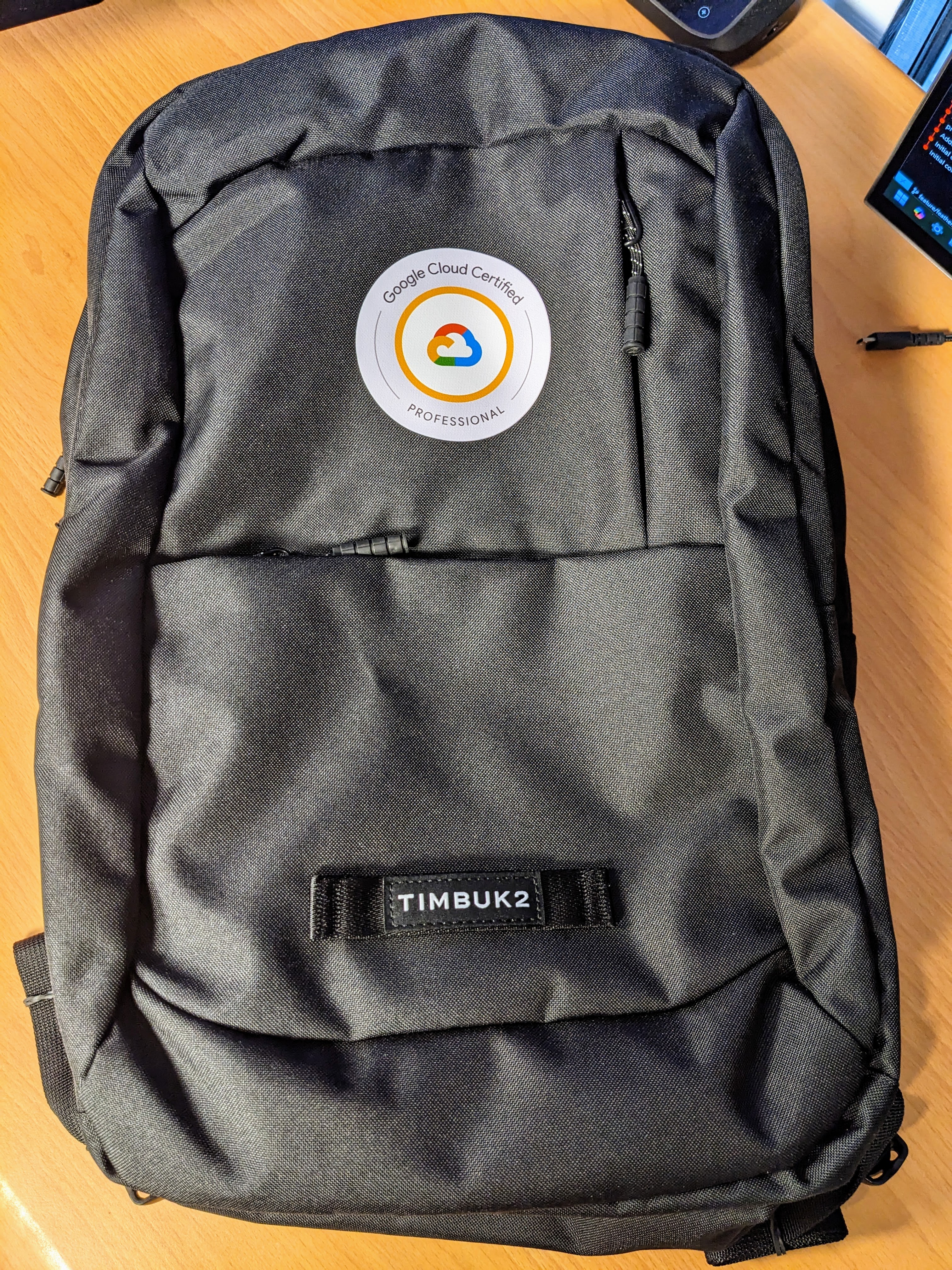 A black Timbuk2 backpack with a round "Google Cloud Certified - PROFESSIONAL" sticker placed on the front.