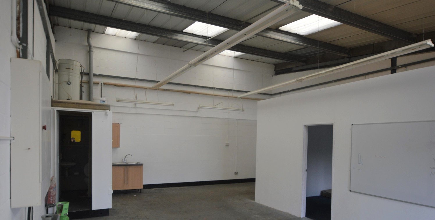 The property comprises a mid-terrace unit of steel frame construction with blockwork walls under a mono-pitched roof with glazed front elevation together with manual up and over loading door. There are 2 car parking spaces to the front of this unit.