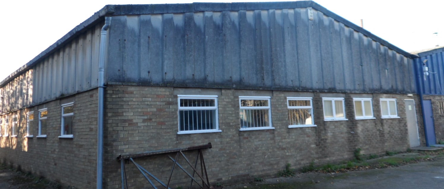 The property comprises a single storey end of terrace industrial building of steel portal frame construction, with cavity brick elevations, part over clad with cement base sheet cladding, beneath a shallow pitched asbestos sheet roof with inset trans...