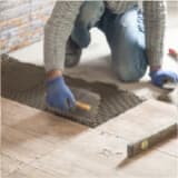 Worker spreading grout on floor for tiles