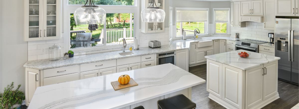 The Cambria quartz backsplash with black and gold hardware against dark green cabinets.