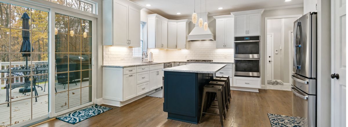 Elegant shaker kitchen with white cabinets, white tile backsplash, marbled Cambria countertops, and a bold blue island.