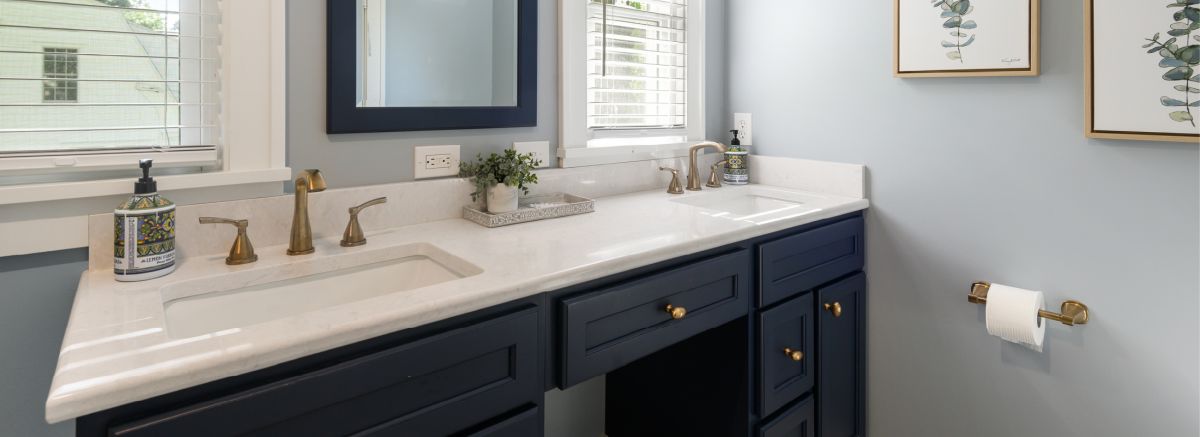 The vanity with blue cabinets, a white Cambria top, and bronze hardware.