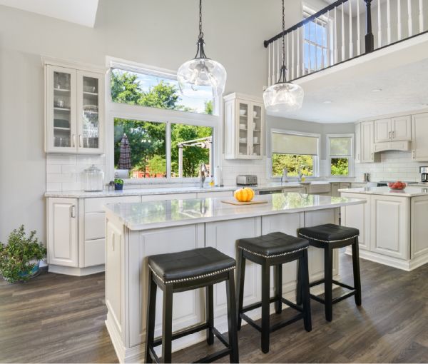 A close up of the Cambria quartz countertop and dark green cabinets with a coffeemaker, glasses, and serveware.