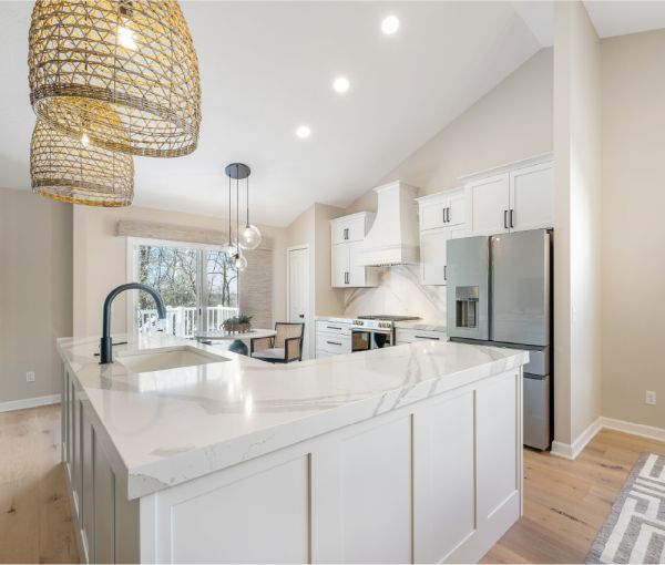 The contemporary kitchen with white cabinets, veined Cambria countertops with a matching full-height backsplash, and concave hood.