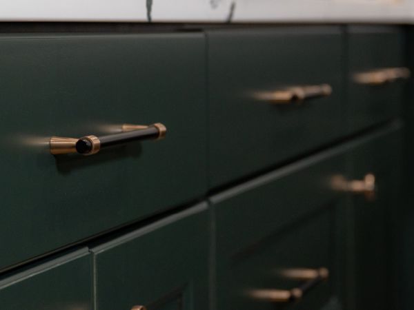 A close up of the dark green cabinets with black and gold pulls.