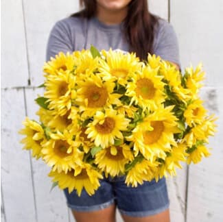 Maggie Troyer holding a boquet of sunflowers from Farm and Table