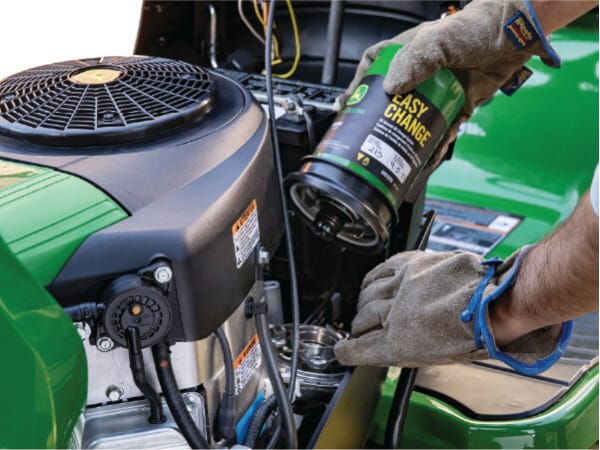 A person changing the oil and filter in a John Deere mower with John Deere Easy Change Oil & Filter.