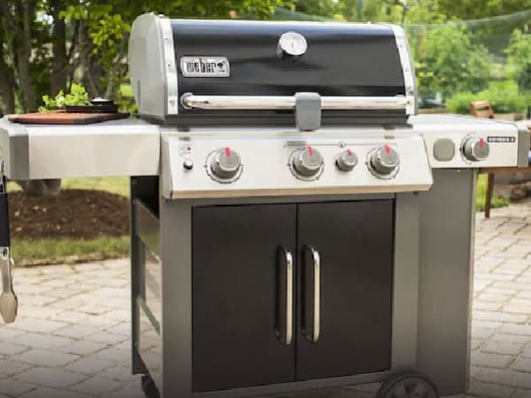 A Weber stainless steel gas grill sitting on a patio