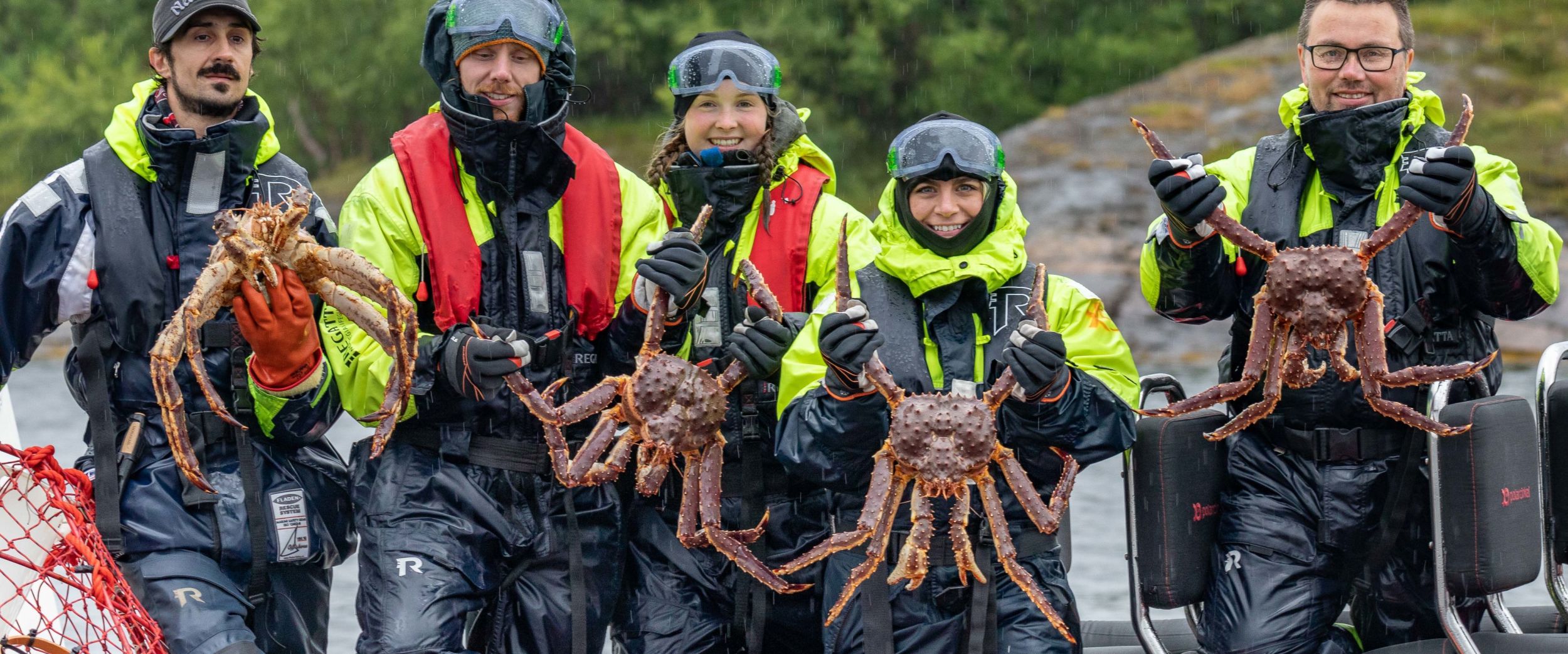 Happy people in a rib holding king crabs.