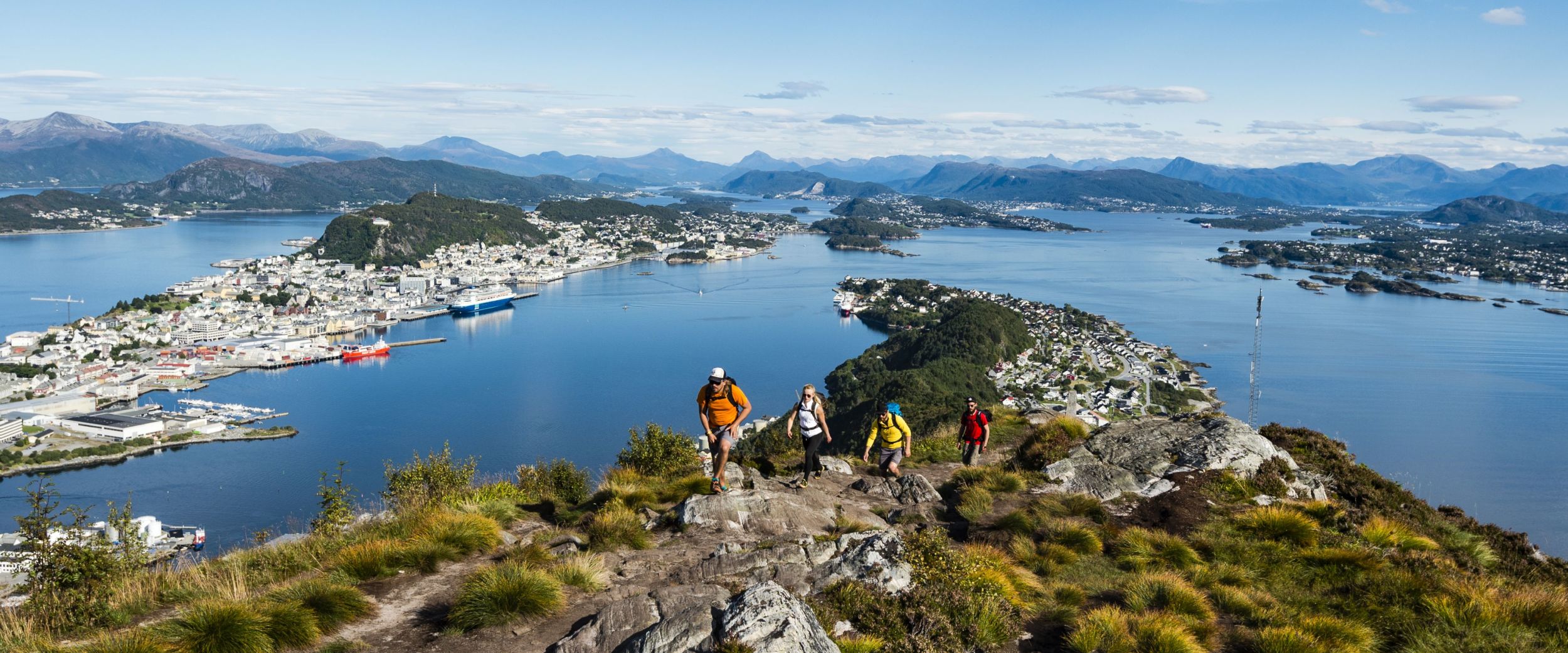 People on a hike to Sukkertoppen with view to Ålesund and the Borgundfjord.