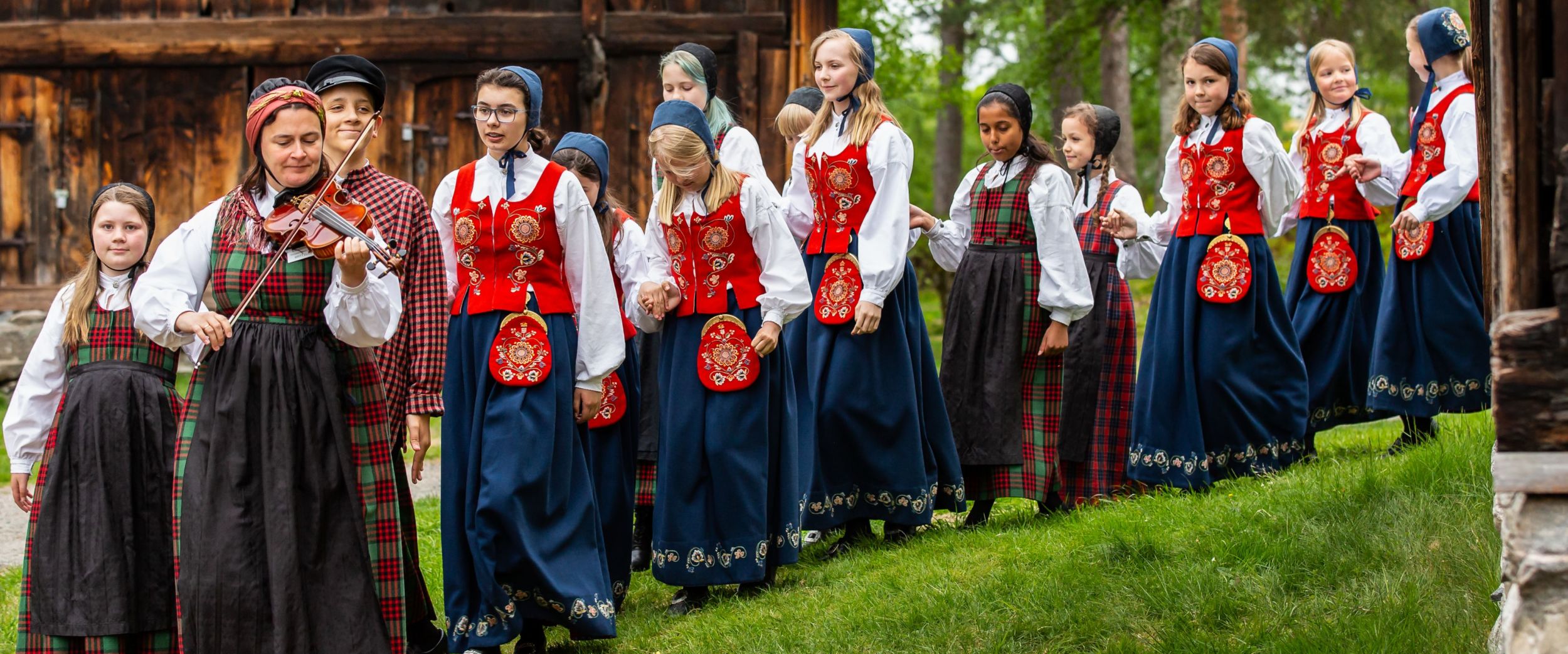 Leikarring at Romsdalsmuseet, woman playing a fiddle and girls in the Norwegian traditional costume Bunad. 