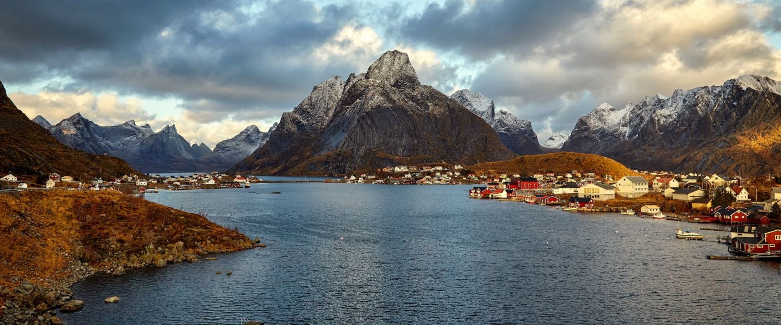 The fishing village Reine with the Lofoten archipelago in the background seen in the sunset with a cloudy sky.