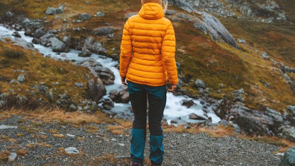 Person wearing an insulated jacket on a rocky trail in the mountains.