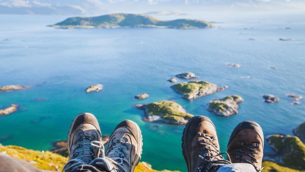 View from a cliff with hiking boots in the foreground overlooking the sea and islands.