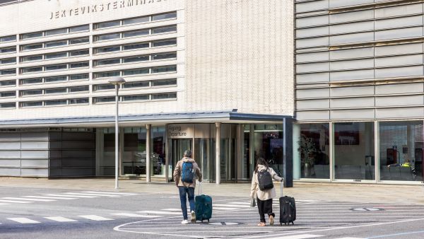 Two travelers with rolling suitcases crossing the street