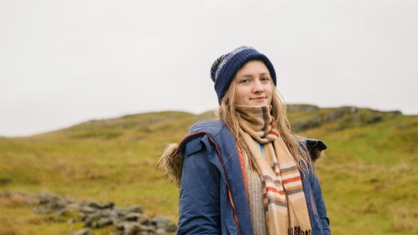 Traveler wearing a beanie, scarf and warm jacket outdoors.
