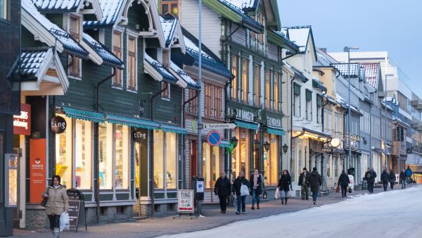 Folk i vinterleg gate med trehus i Tromsø