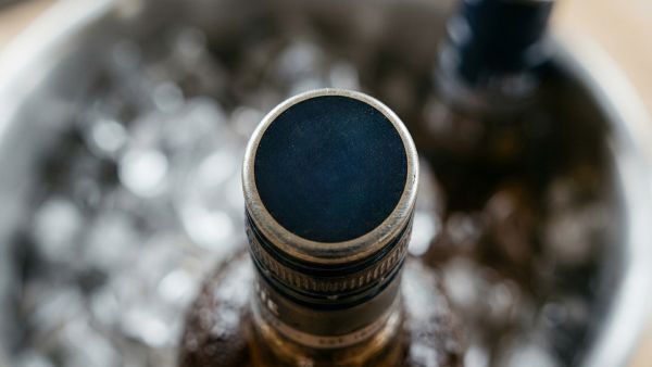 Close-up of a bottle cap in an ice bucket, with bottles and ice softly blurred in the background.