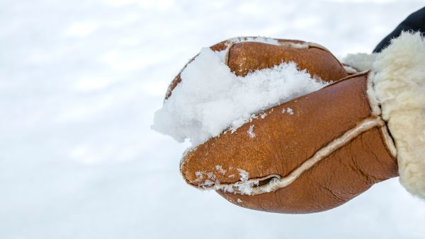 Close-up of warm insulated mittens in the snow, ideal for cold Norwegian winter weather.