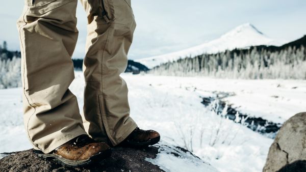 Close-up of boots standing on a rock in a snowy landscape.