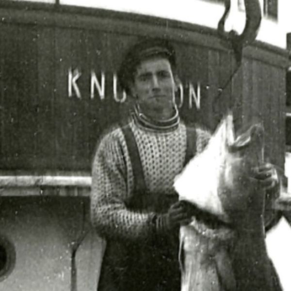 Per as a young man holding up a big fish he has cought