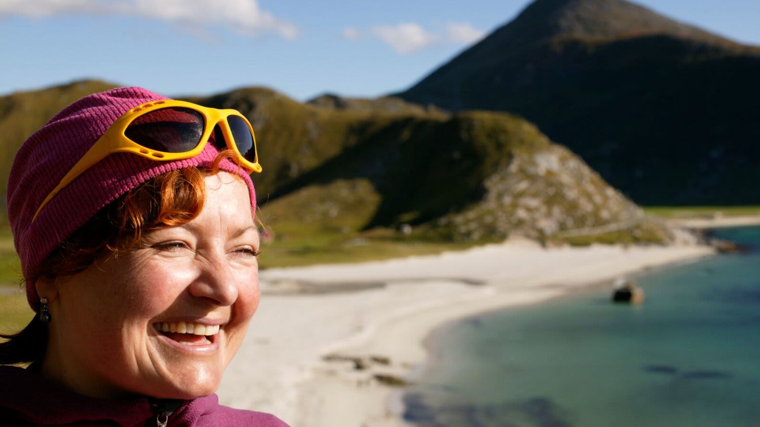 A smiling woman at Hauklandstranda beach in Lofoten. Photo: Nils Erik Bjørholt, visitnorway.com