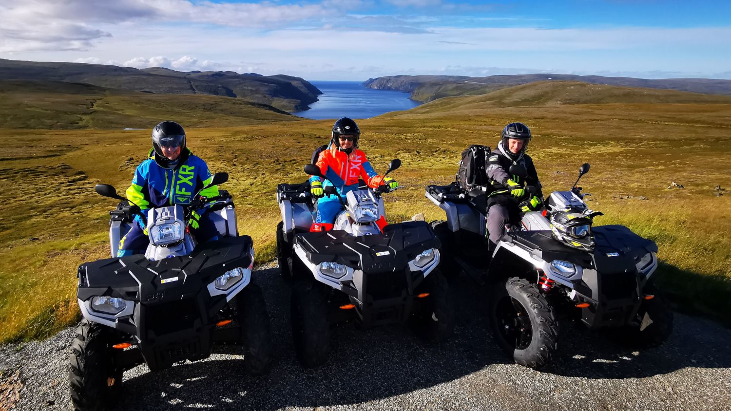 Guests on ATVs during a guided safari from Honningsvåg to the North Cape, stopping for photos with wide Arctic landscapes and fjords in the background.