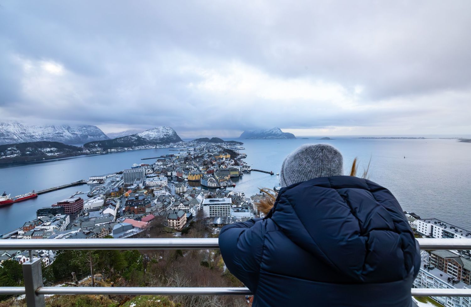 A guest standing on the view point of Fjellstua on Mount Aksla in Ålesund overlooking the town of Ålesund