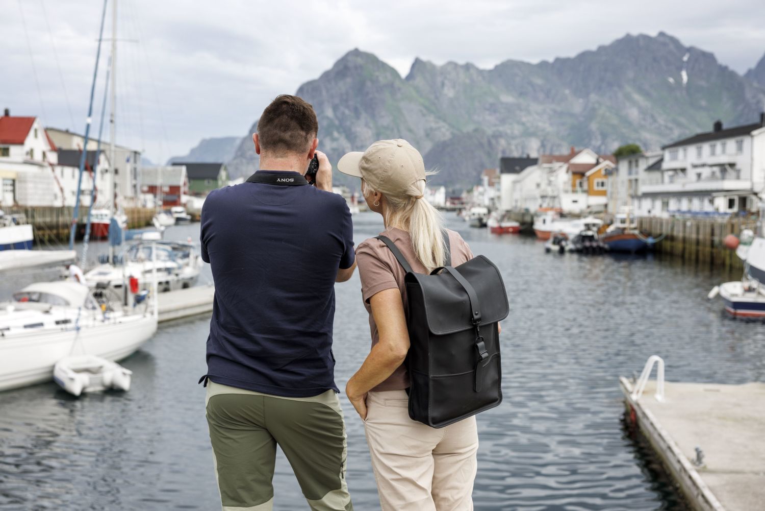 couple taking photos of the mountains in henningsvær