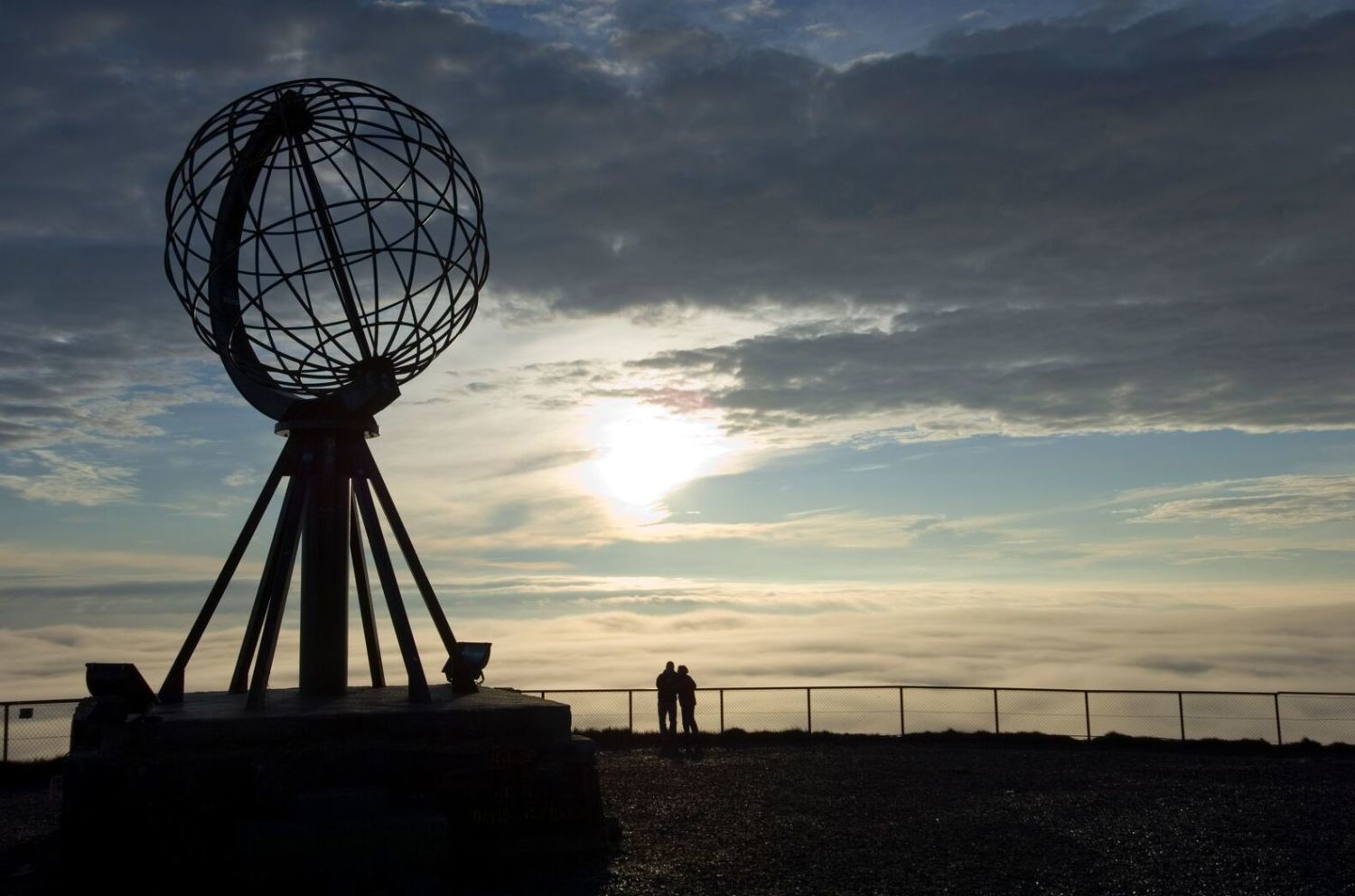 People watching the midnight sun next to the globe at the North Cape. Photo: Johan Wildhagen, visitnorway.com