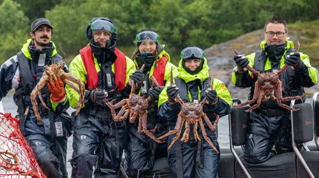 Happy people in a rib holding king crabs.