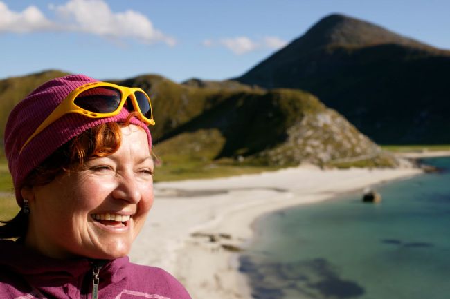 A smiling woman at Hauklandstranda beach in Lofoten. Photo: Nils Erik Bjørholt, visitnorway.com