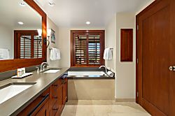 Beach Villas at Ko Olina O-1402 - Elegant primary bathroom with large mirror, dual sinks, and soaking tub.