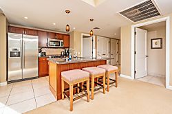 Honua Kai Hokulani 620 - Warm island kitchen with bar seating, stainless appliances, inviting design.