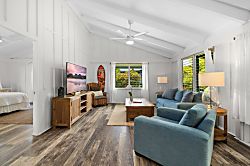 Hale Kanani Steps to Hanalei Bay  - Afternoon light settles across the living room, catching the greenery just outside the win