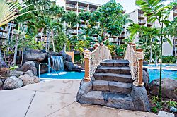Aston Kaanapali Shores 1G4 - A tropical-themed pool area features a waterfall, rope bridge, and lush landscaping surrou