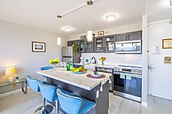 Waikiki Banyan 3401 T2 - Modern kitchen with a marble island and blue bar stools for casual dining.