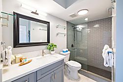 Waikiki Banyan 3401 T2 - Modern bathroom with a glass-enclosed shower and marble countertop.
