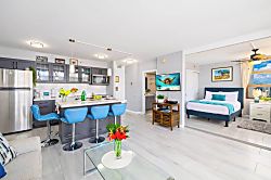 Waikiki Banyan 3401 T2 - Modern kitchen and living area with blue bar stools and a bright bedroom with city views.