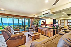 Oceanfront Oasis in Lahaina - Spacious living room with plush recliners, tropical décor, and a large TV, opening to floo