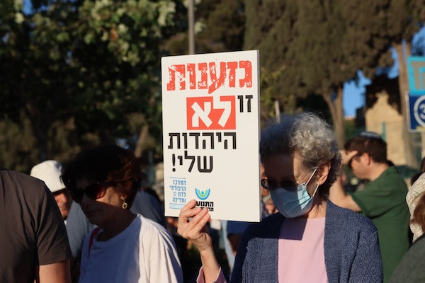 A man holding a sign in Hebrew and Arabic "One world, one humanity" (Photo: Sharona Weiss)