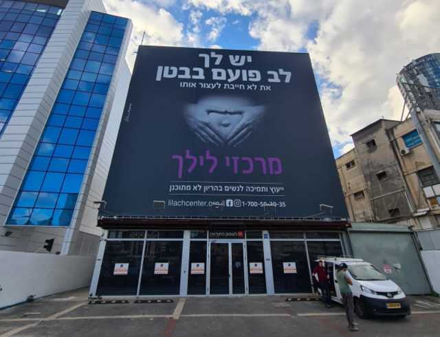Sandy Shoshani, director of Be'ad Chaim, shows a calendar the organization creates with pictures of babies saved through their work (Photo: Screenshot)