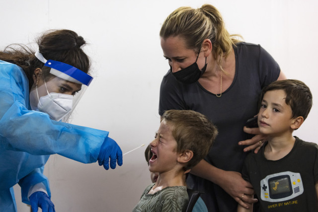 Magen David medical worker performs a COVID-19 rapid antigen test on children at a test complex in Jerusalem, August 18, 2021. (Photo: Olivier Fitoussi/Flash90)