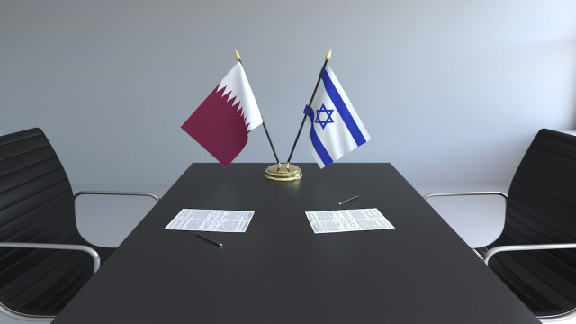 Illustrative negotiating table with Israeli and Qatari flags (Image: Shutterstock)