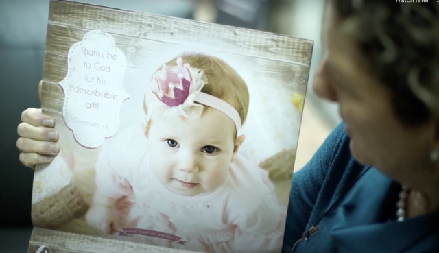 Sandy Shoshani, director of Be'ad Chaim, shows a calendar the organization creates with pictures of babies saved through their work (Photo: Screenshot)