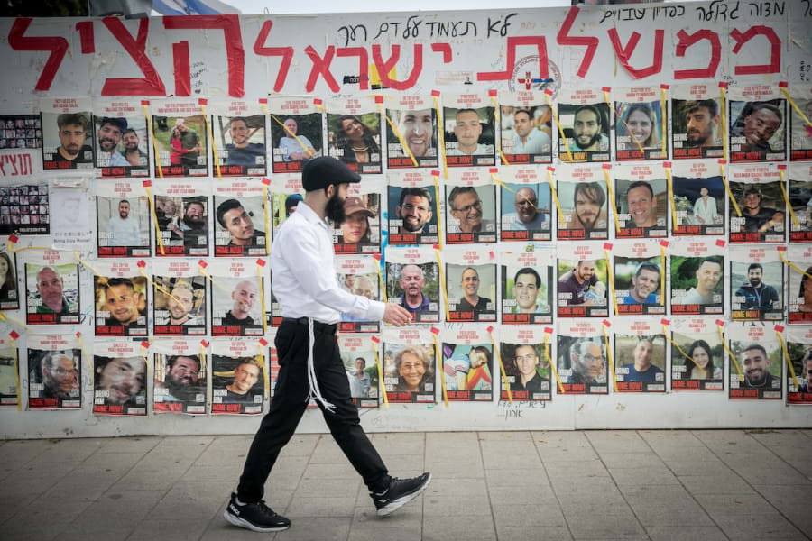 People walk by photographs of Israelis still held hostage by Hamas terrorists in Gaza, at "Hostage Square" in Tel Aviv. May 1, 2024. (Photo: Miriam Alster/Flash90)