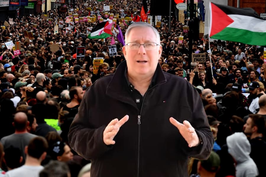Joel Rosenberg with protestors waving Palestinian flags in the background, (Photo: ALL ISRAEL NEWS, REUTERS/Chris J Ratcliffe)