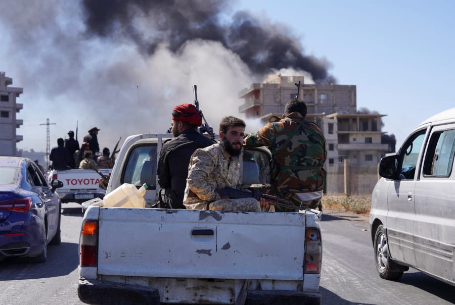 Smoke rises while Syrian security forces sit in the back of a truck as Syrian troops entered the predominantly Druze city of Sweida on Tuesday following two days of clashes, in Sweida, Syria July 15, 2025. Photo: REUTERS