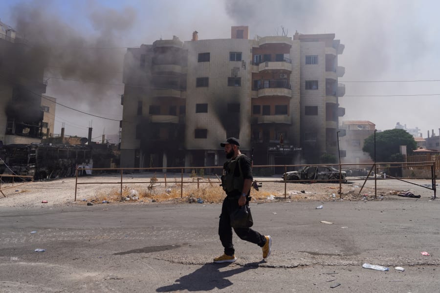De la fumée s'élève alors qu'un combattant bédouin marche dans une rue, suite à l'annonce par la présidence syrienne d'un cessez-le-feu après des jours de violence dans la province de Sweida, déclenchée par des affrontements entre des combattants bédouins et des factions druzes, à Sweida, en Syrie, le 19 juillet 2025. Le 19 juillet 2025, à Sweida, en Syrie : REUTERS par Karam al-Masri